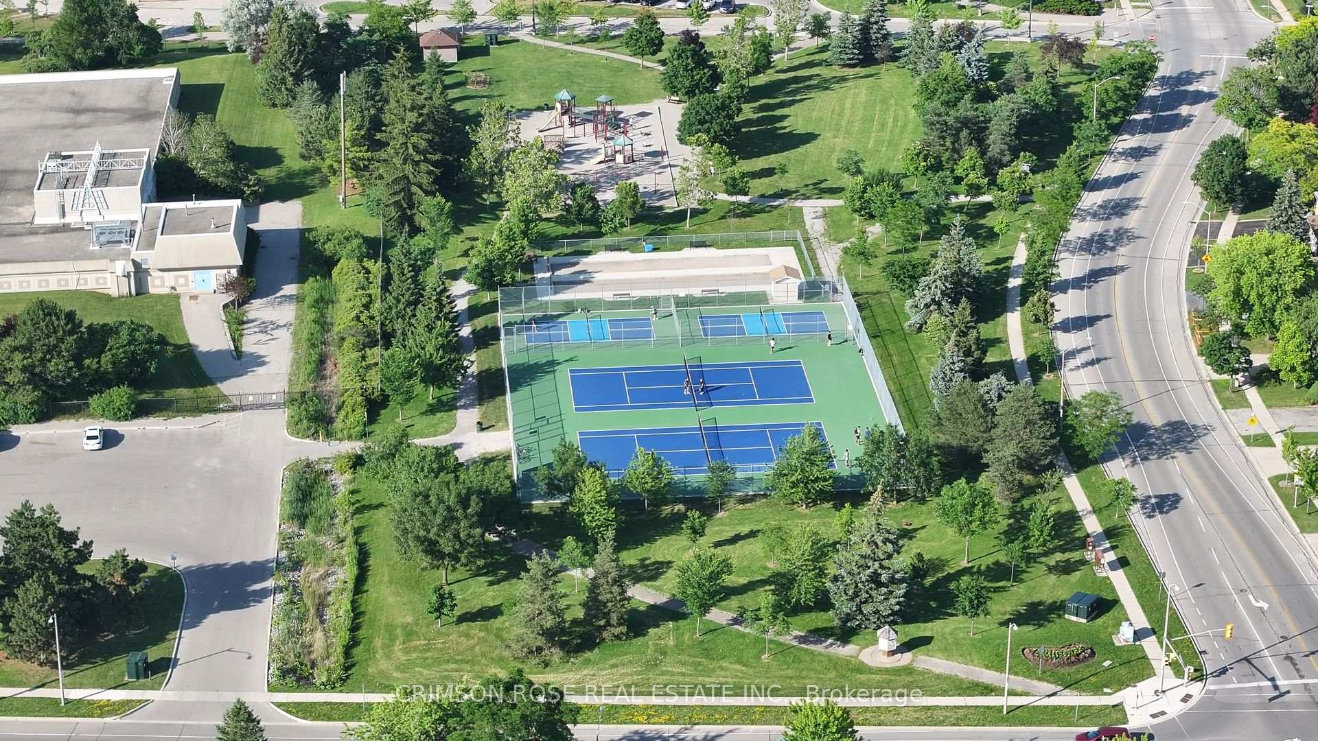 Aerial view of a park with tennis courts, a playground, and tree-lined walking paths.