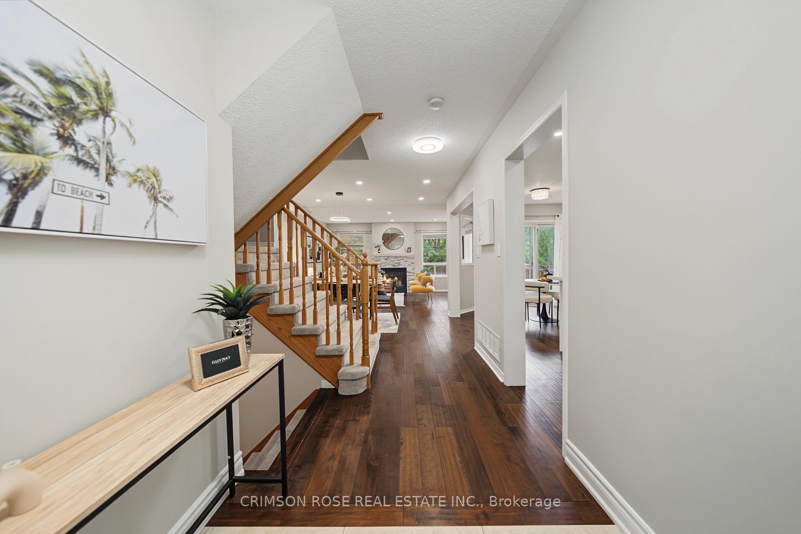 Foyer with a carpeted wood staircase, dark hardwood floors, and views toward the living room and dining area.