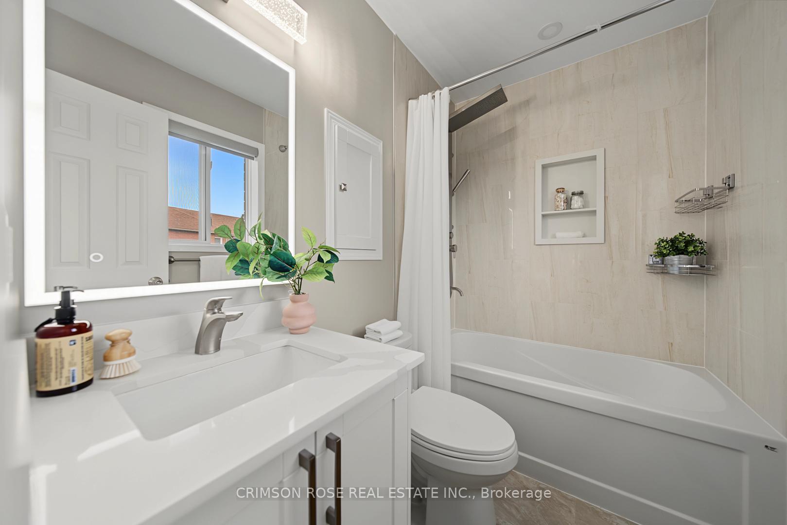 Bathroom with a white vanity, toilet, and tiled bathtub with a rainfall showerhead.