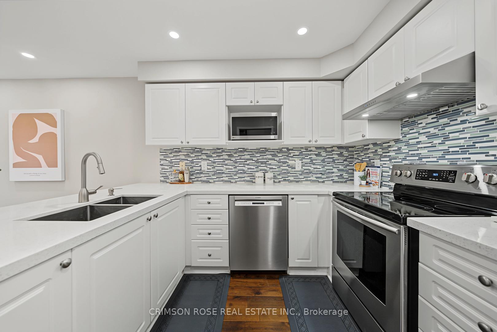 Kitchen with white shaker cabinets, stainless steel appliances, and a blue-gray mosaic tile backsplash.
