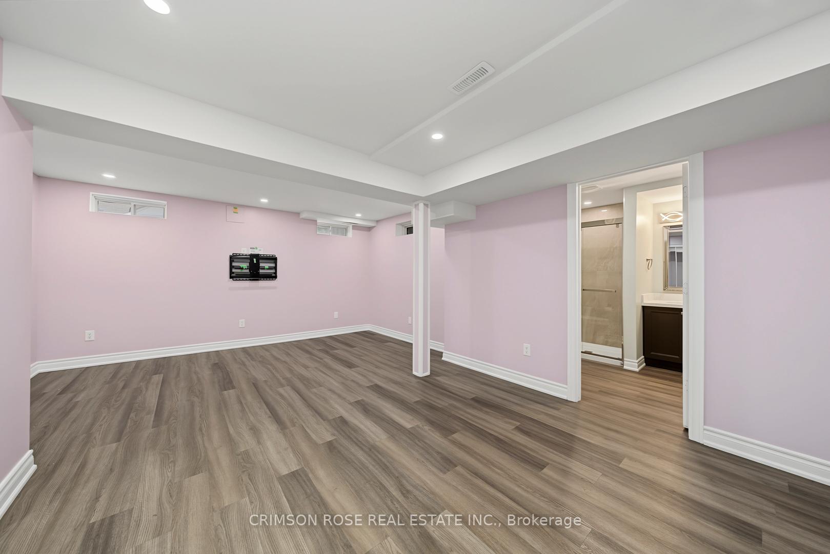 Finished basement room with pink walls, gray flooring, and an open doorway to a bathroom.