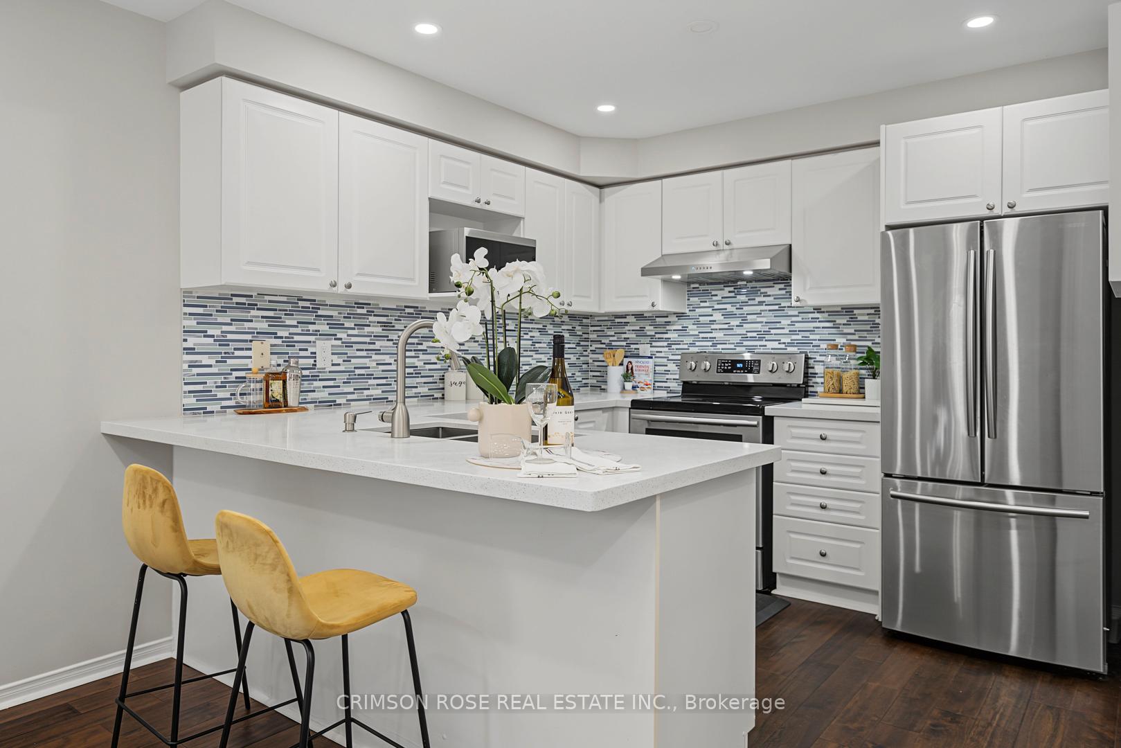 Bright kitchen with white cabinets, mosaic backsplash, stainless appliances, and a large island with yellow stools.