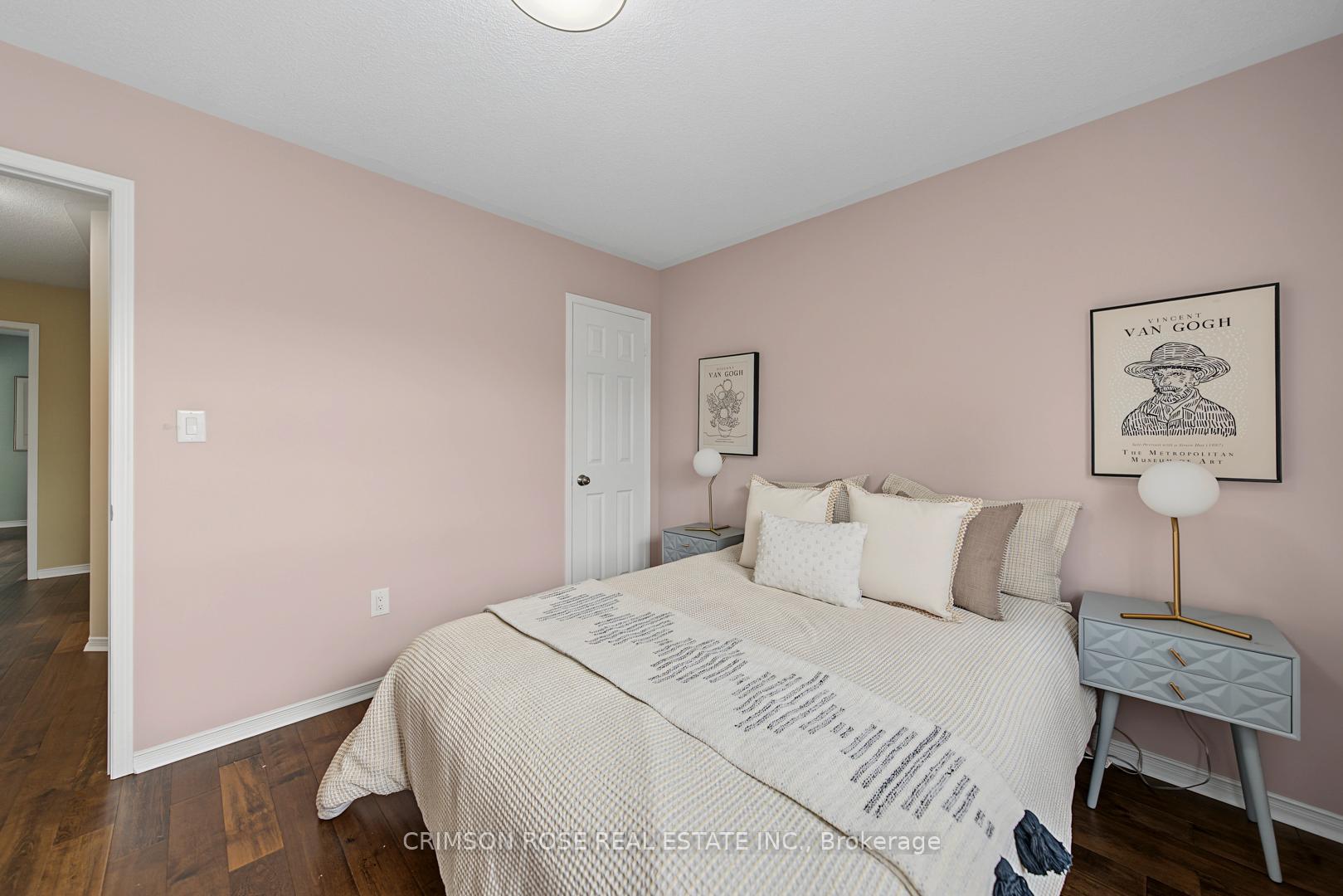 Staged bedroom with a white bed, blush-pink walls, blue-gray nightstands, and framed Van Gogh prints.