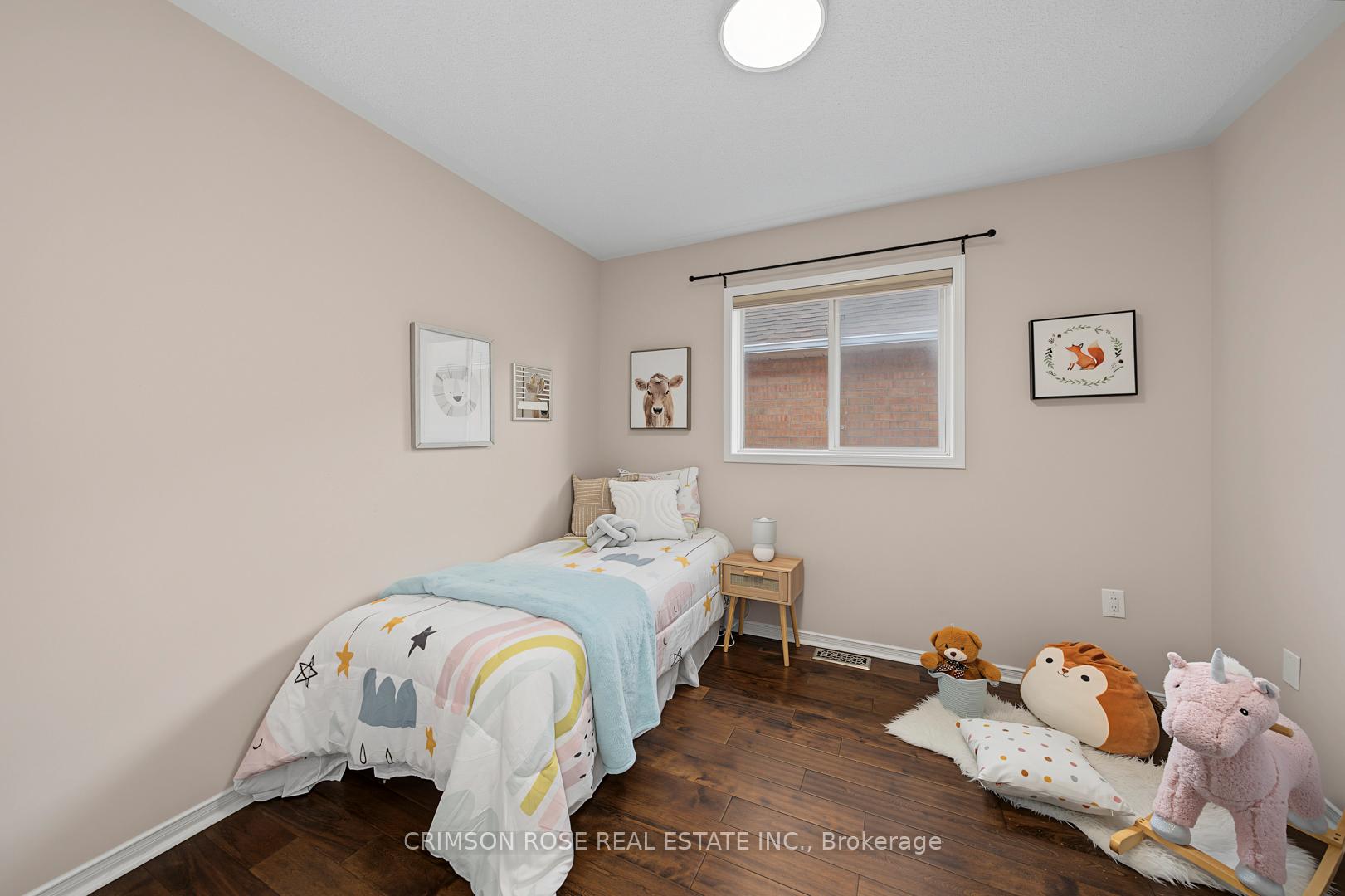 Child's bedroom with a single bed, star-and-rainbow bedding, stuffed animals, and dark wood flooring.