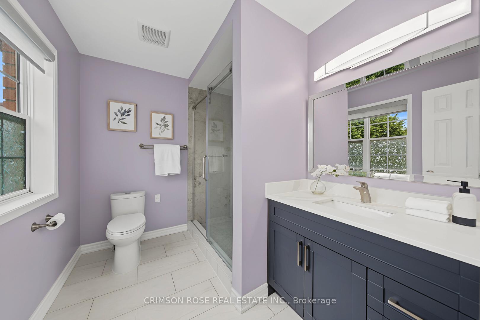 Bathroom with a glass shower, navy vanity, and lavender walls.