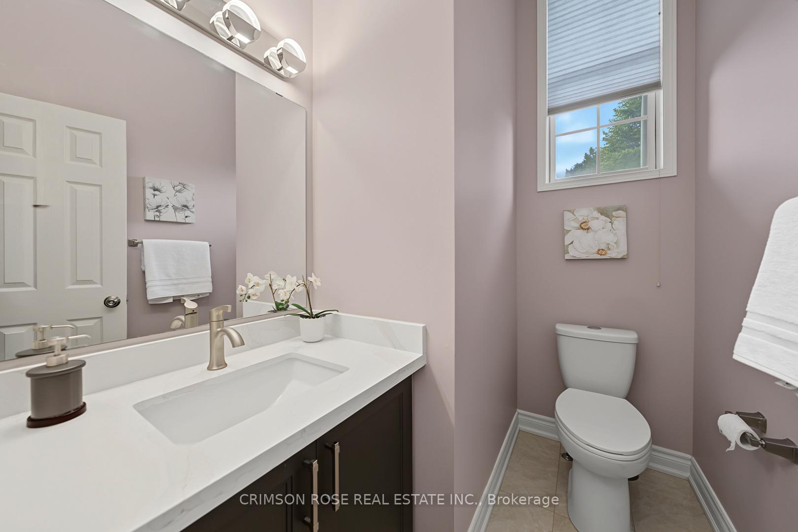 Bathroom with a dark vanity, white countertop, toilet, and high window with a partially lowered blind.