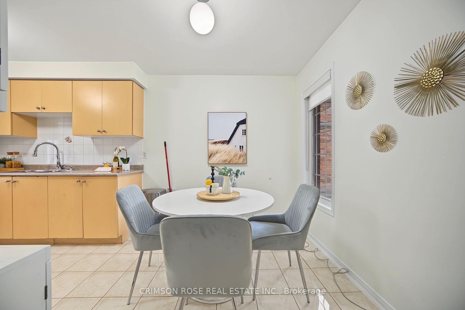 Kitchen and dining area with light wood cabinets, a round white table, gray chairs, and gold wall decorations.