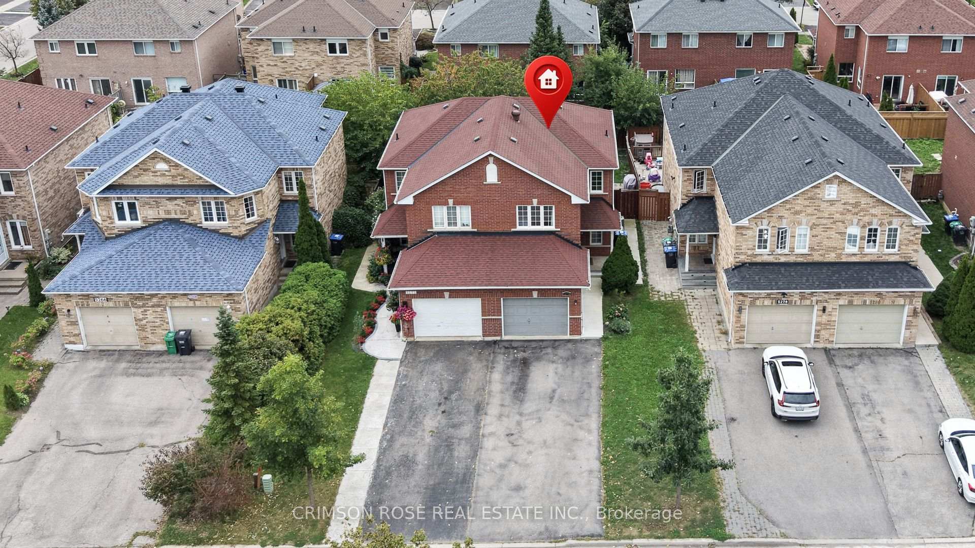 Aerial view of a red-brick house with a reddish roof and attached double garage, marked by a red house pin.