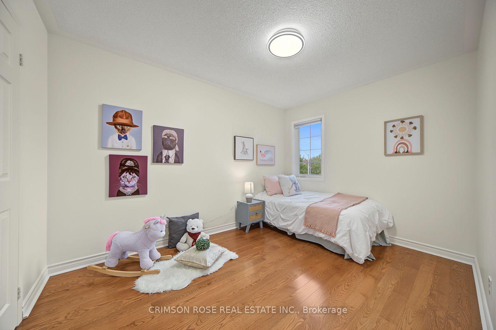 Staged bedroom with a white bed, pink throw, hardwood floors, plush toys, and playful animal artwork.