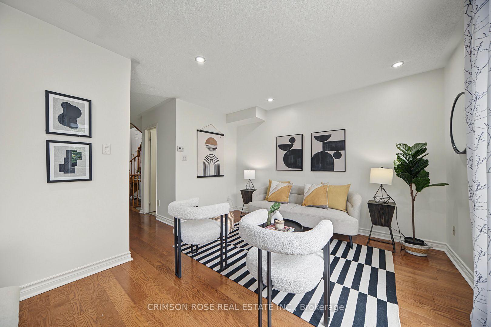 Staged living room with a gray sofa, mustard pillows, striped rug, and warm hardwood floors.