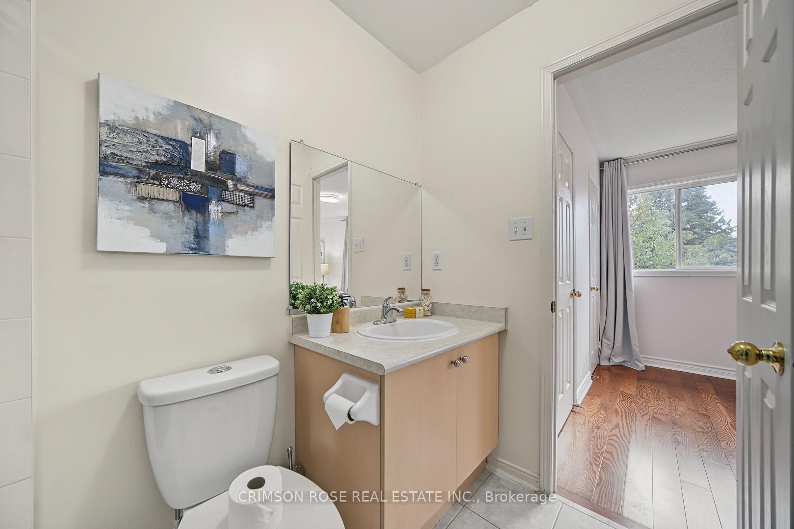 Bathroom with a light wood vanity, large mirror, and doorway to a hardwood-floored room.