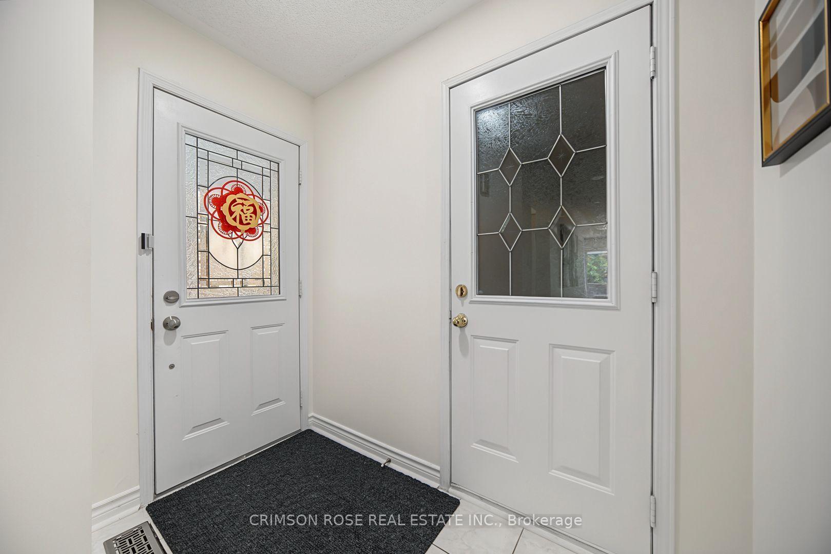 Entry foyer with two white doors featuring decorative glass panels and a dark floor mat.