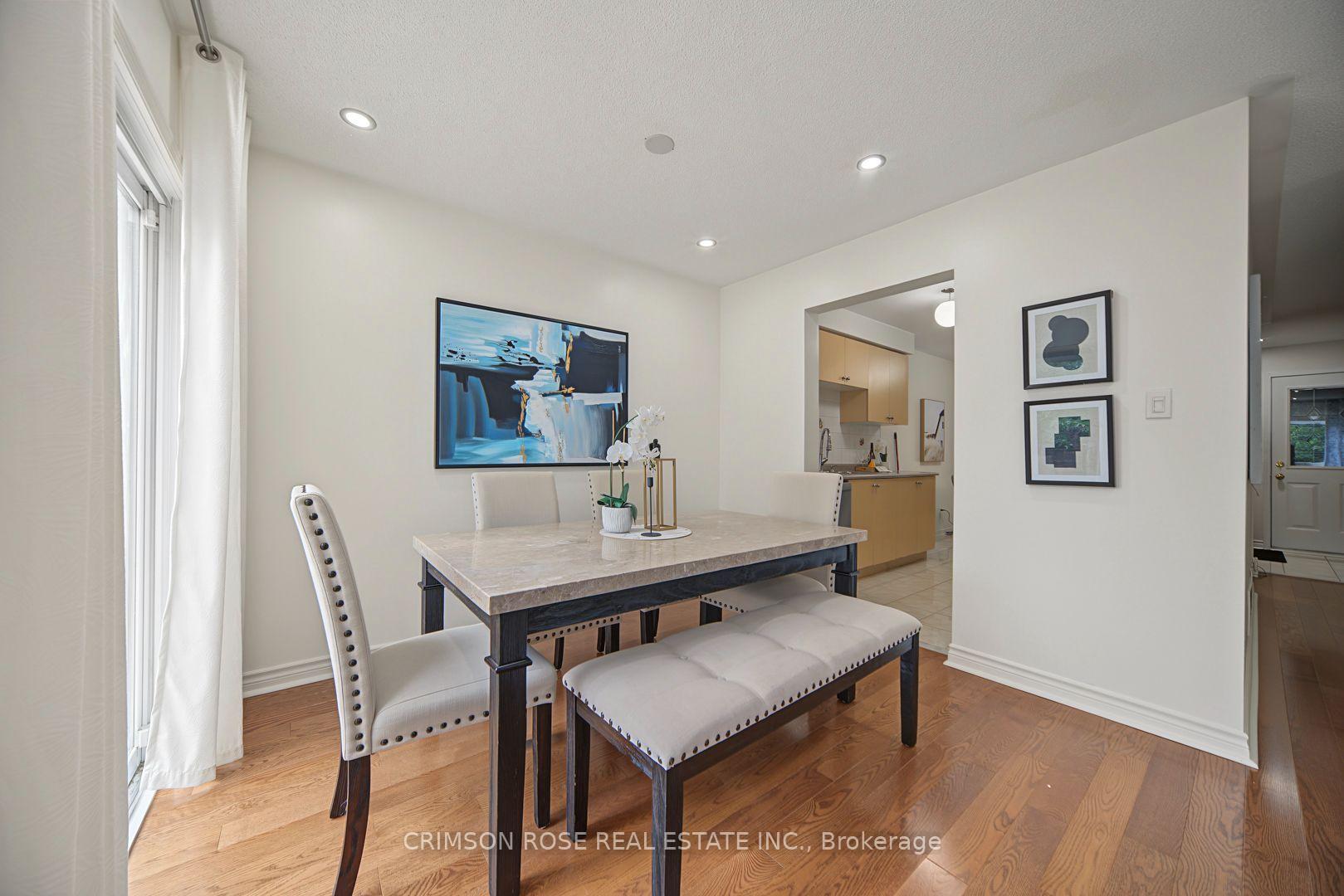 Dining room with a dark wood table, upholstered seating, hardwood floors, and an opening to the kitchen.
