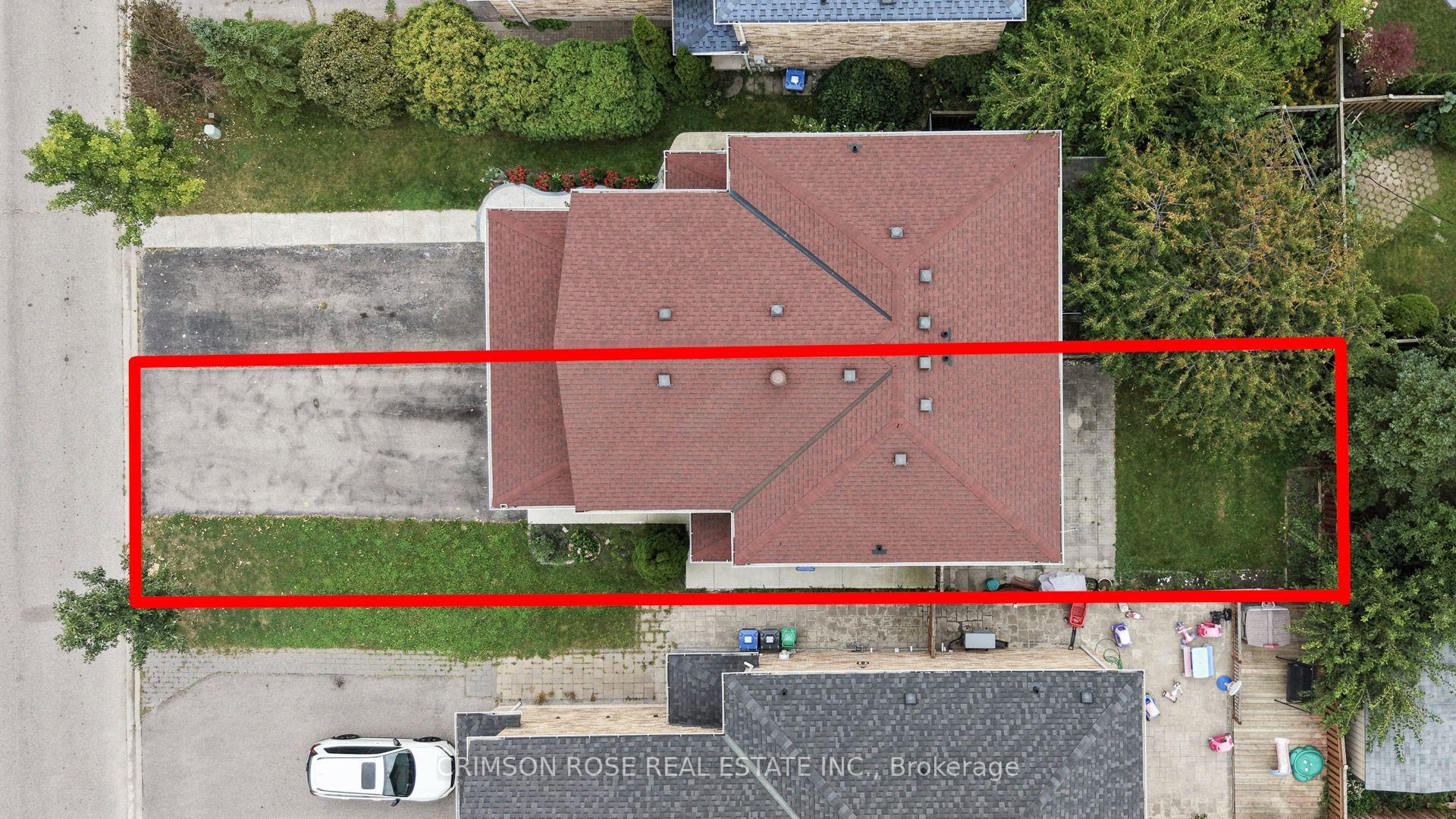 Aerial view of a house and red-outlined lot, with a broad driveway and surrounding lawn.