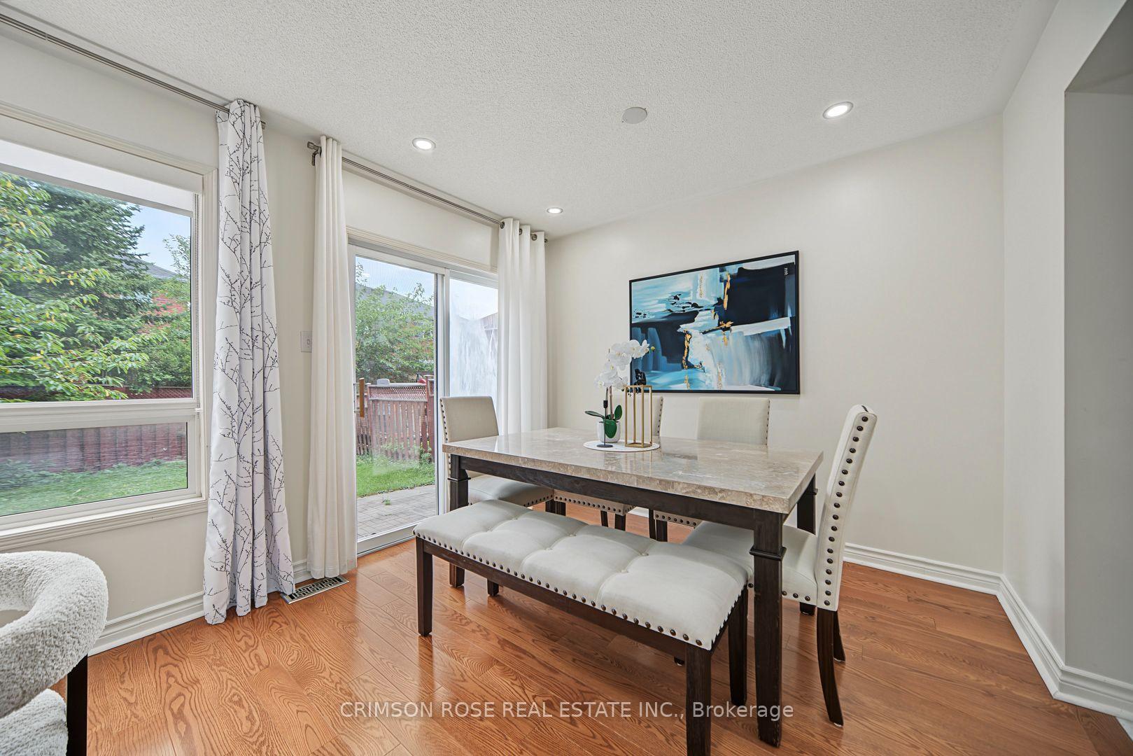 Dining room with a marble-look table, upholstered seating, hardwood floors, and sliding glass doors to the garden.