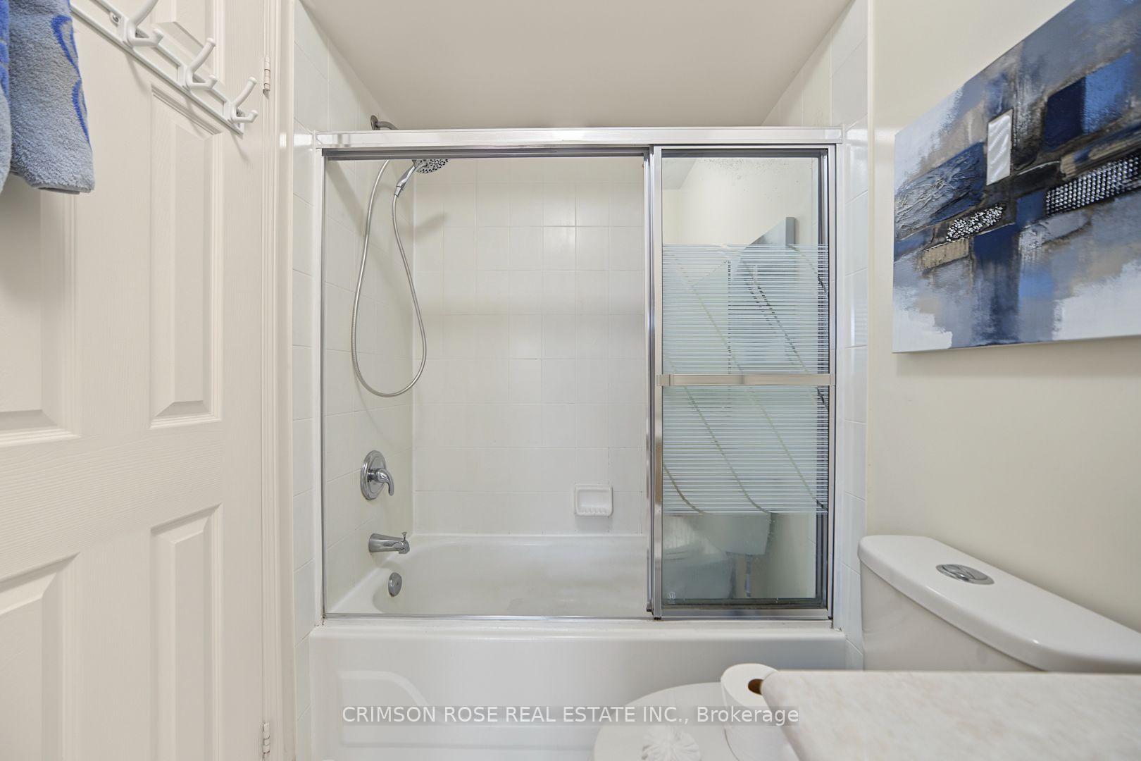 Bathroom with a white tub-shower, sliding glass doors, chrome fixtures, and blue abstract wall art.