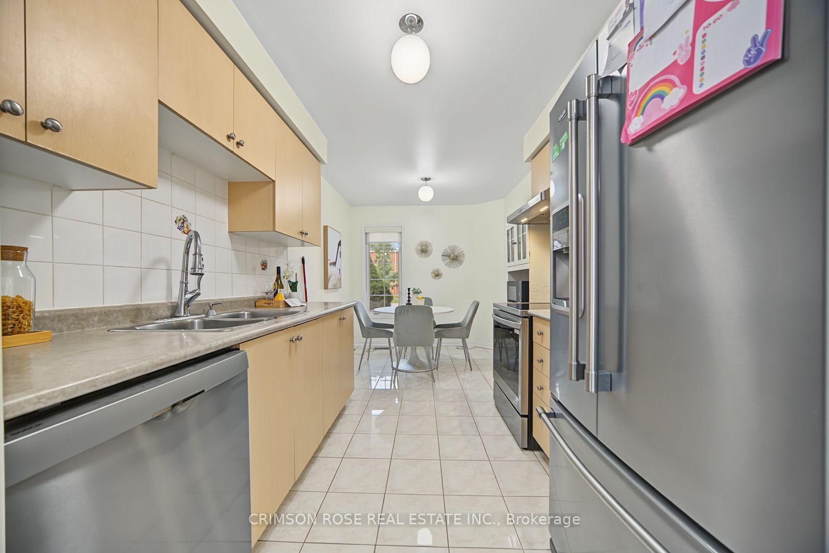 Kitchen with light wood cabinets, stainless steel appliances, and a dining table at the far end.