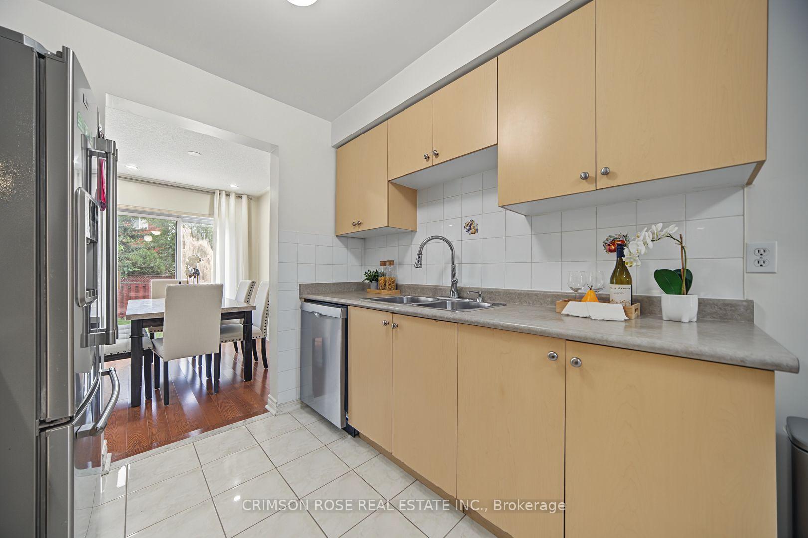 Kitchen with light wood cabinets and stainless steel appliances, opening to a dining area beside a sliding glass door.