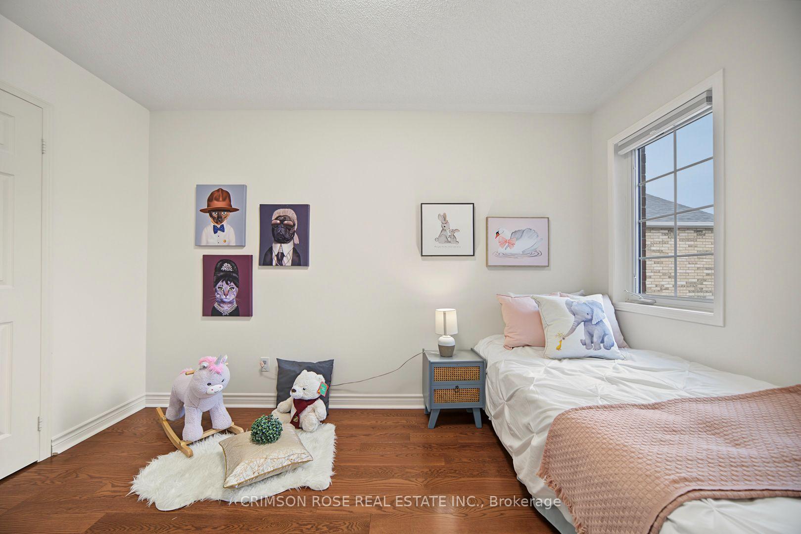 Bedroom with a white bed, pink quilt, animal artwork, and hardwood flooring.