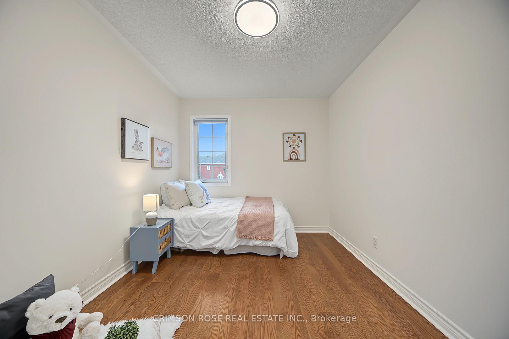 Staged bedroom with a white bed, blue bedside table, and warm wood flooring.