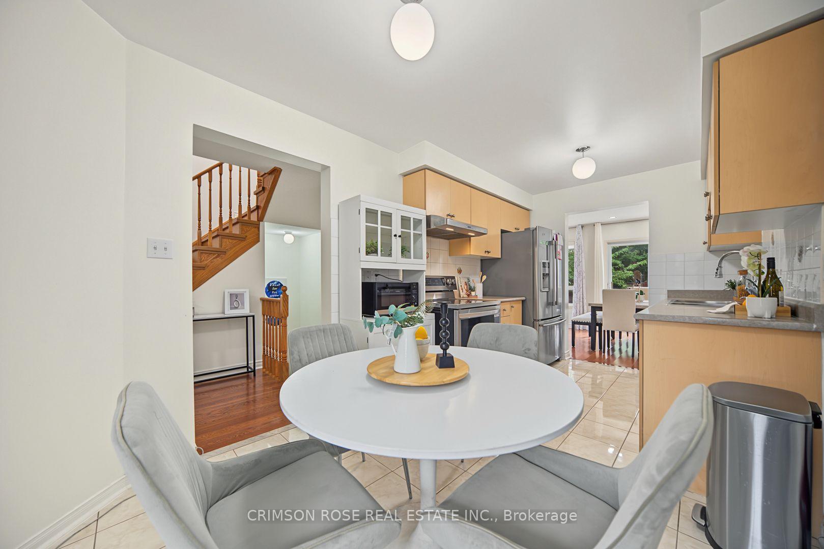 Kitchen and dining area with light wood cabinets, stainless steel appliances, and a round white table.