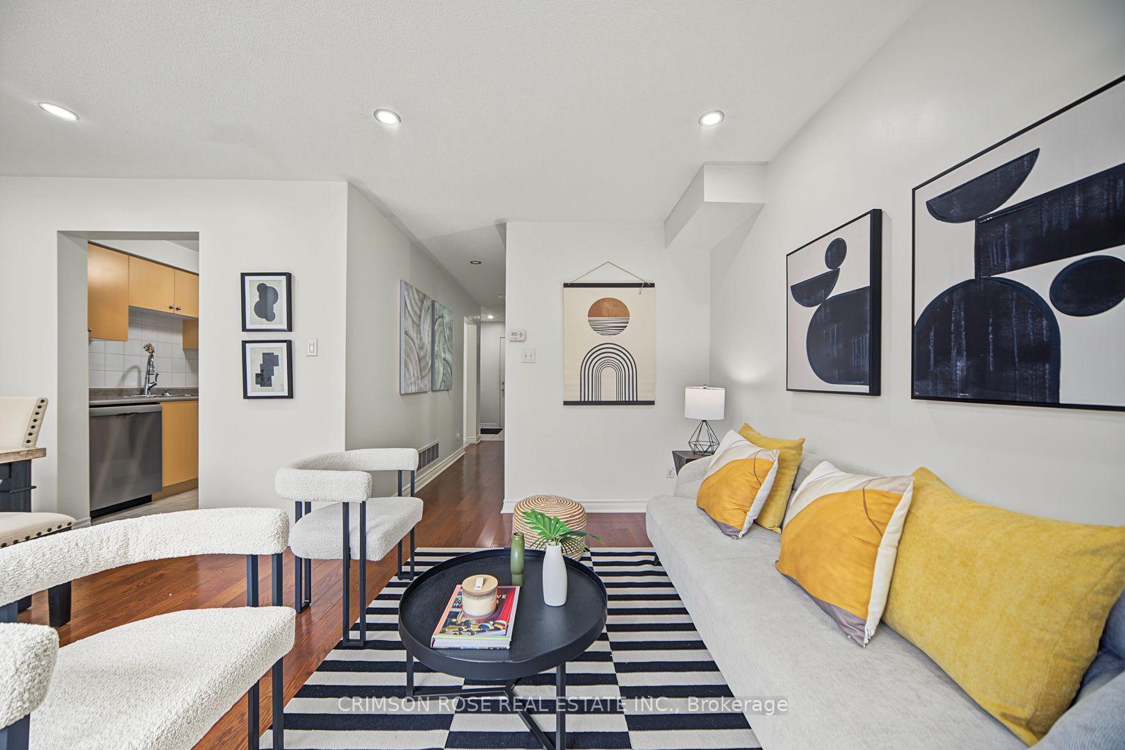 Staged living room with a light sofa, mustard-yellow cushions, abstract art, and a striped rug.