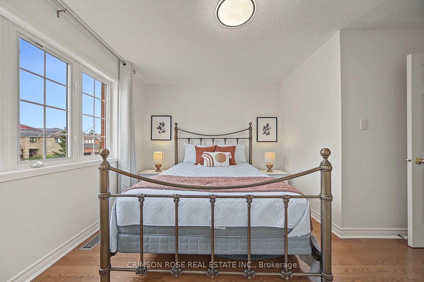 Staged bedroom with a bronze four-poster bed and large gridded windows.
