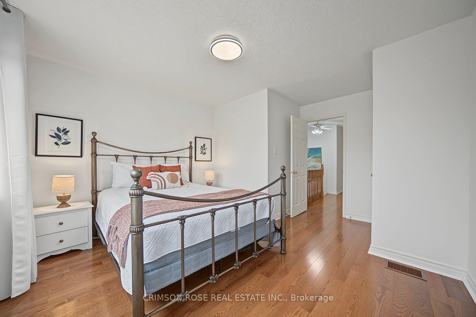 Staged bedroom with a metal four-poster bed, hardwood floors, and an open doorway to the hall.