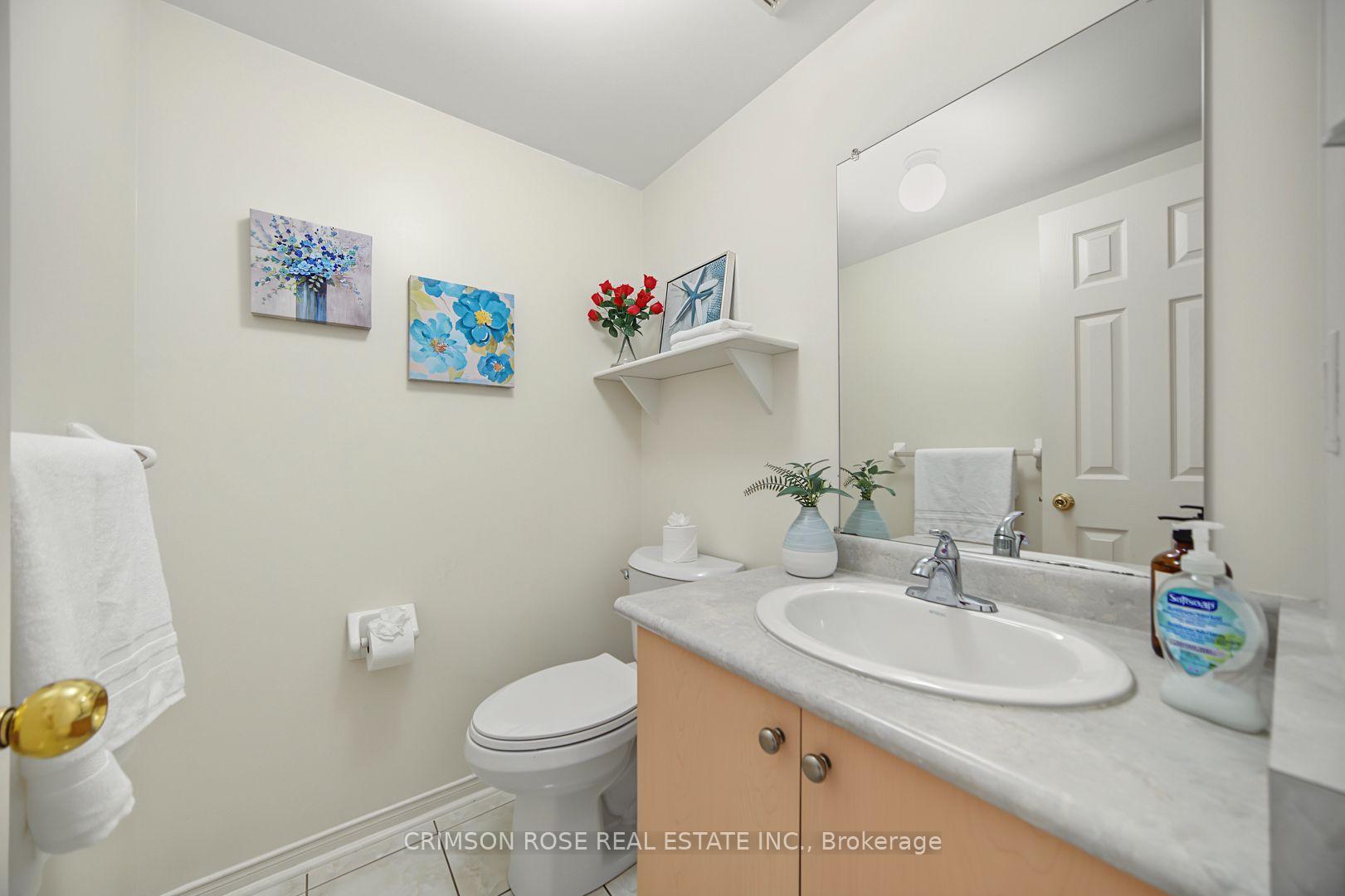 Bathroom with a light wood vanity, large mirror, white toilet, and floral wall art.
