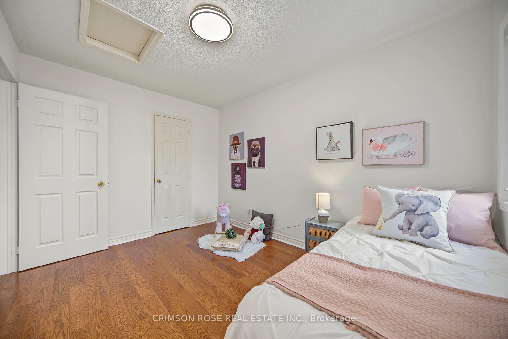Staged bedroom with hardwood floors, pink bedding, elephant-print pillows, and framed animal artwork.