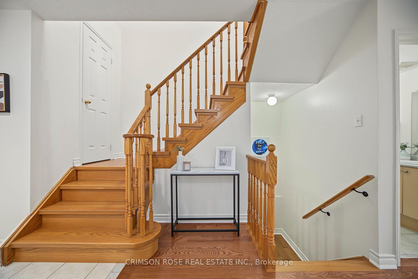 Foyer staircase with honey-toned wood railings and a slim console table beneath.