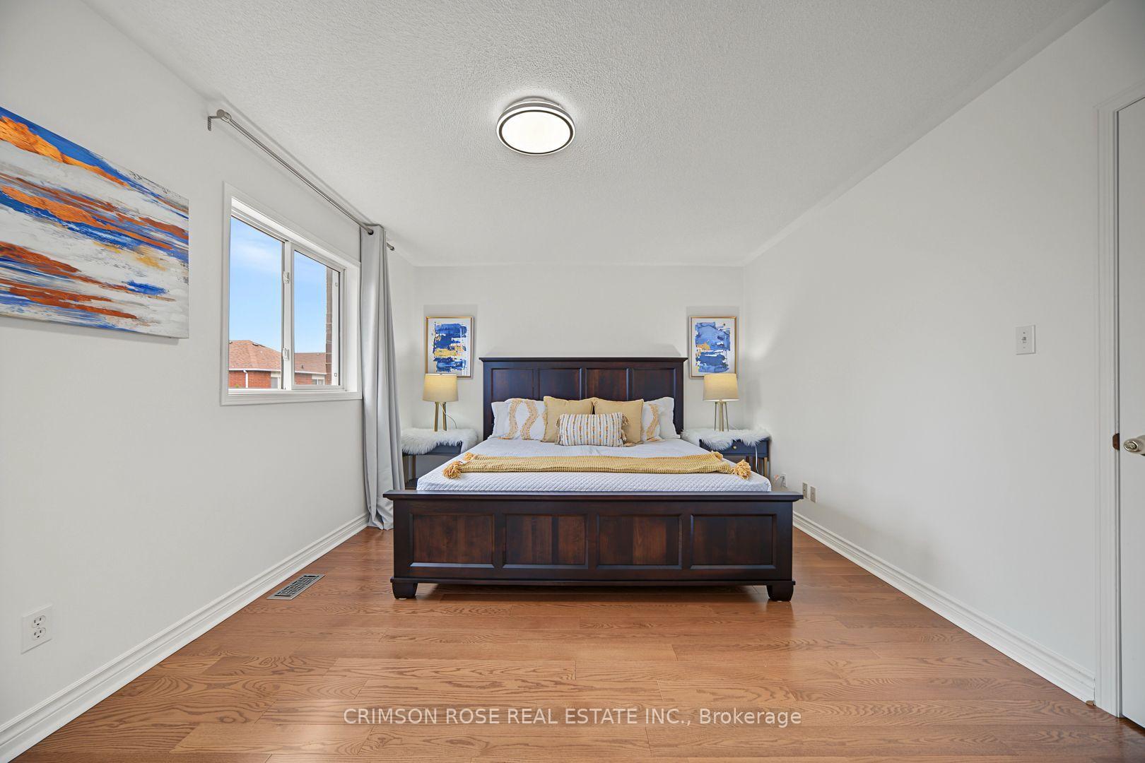 Furnished bedroom with a dark wood bed, gold-accented bedding, hardwood floors, and a curtained window.