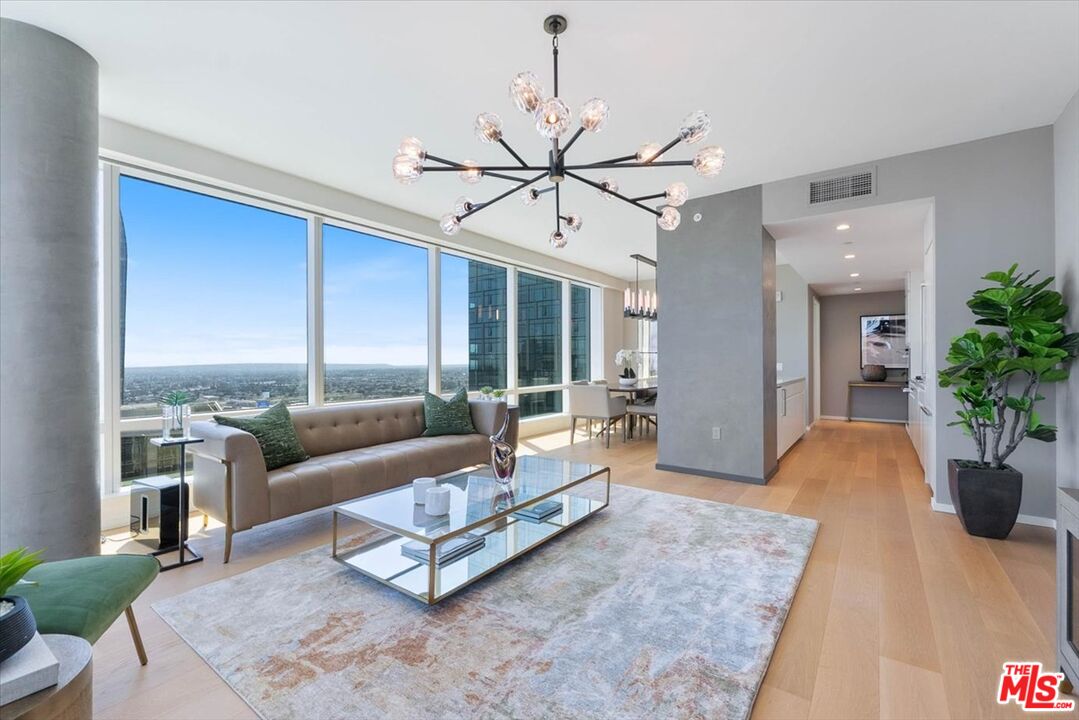 Modern living room with floor-to-ceiling windows overlooking the city and a sculptural chandelier.