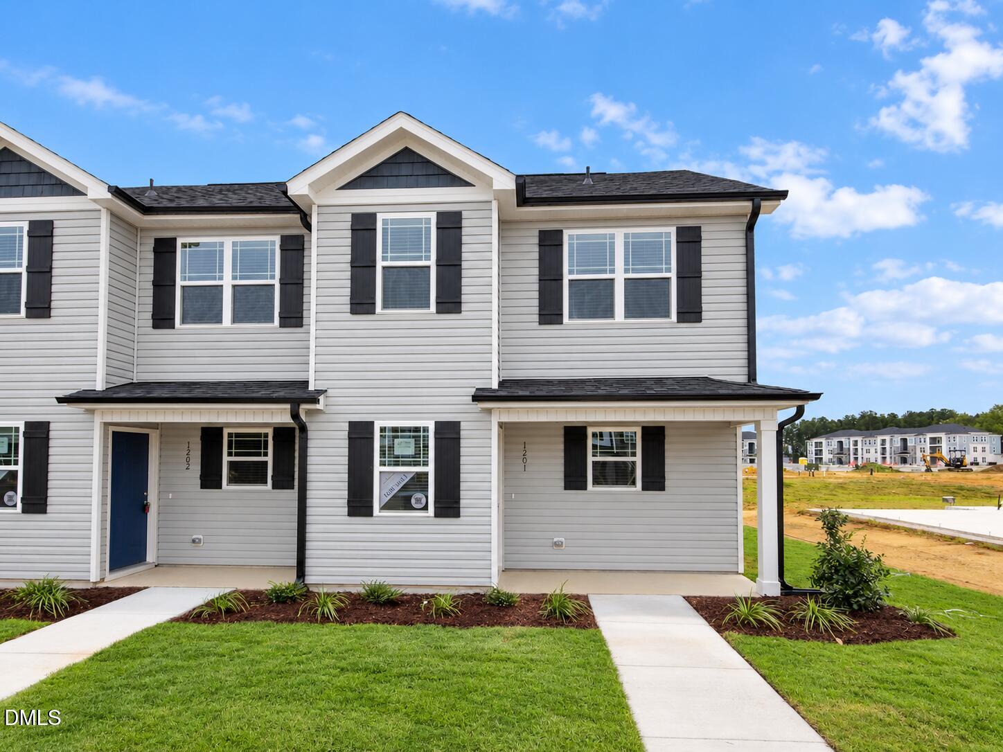 Front exterior of the end-unit townhome at 1201 Brookrun Drive in Oxford, NC, with light gray siding, black shutters, and a covered porch.