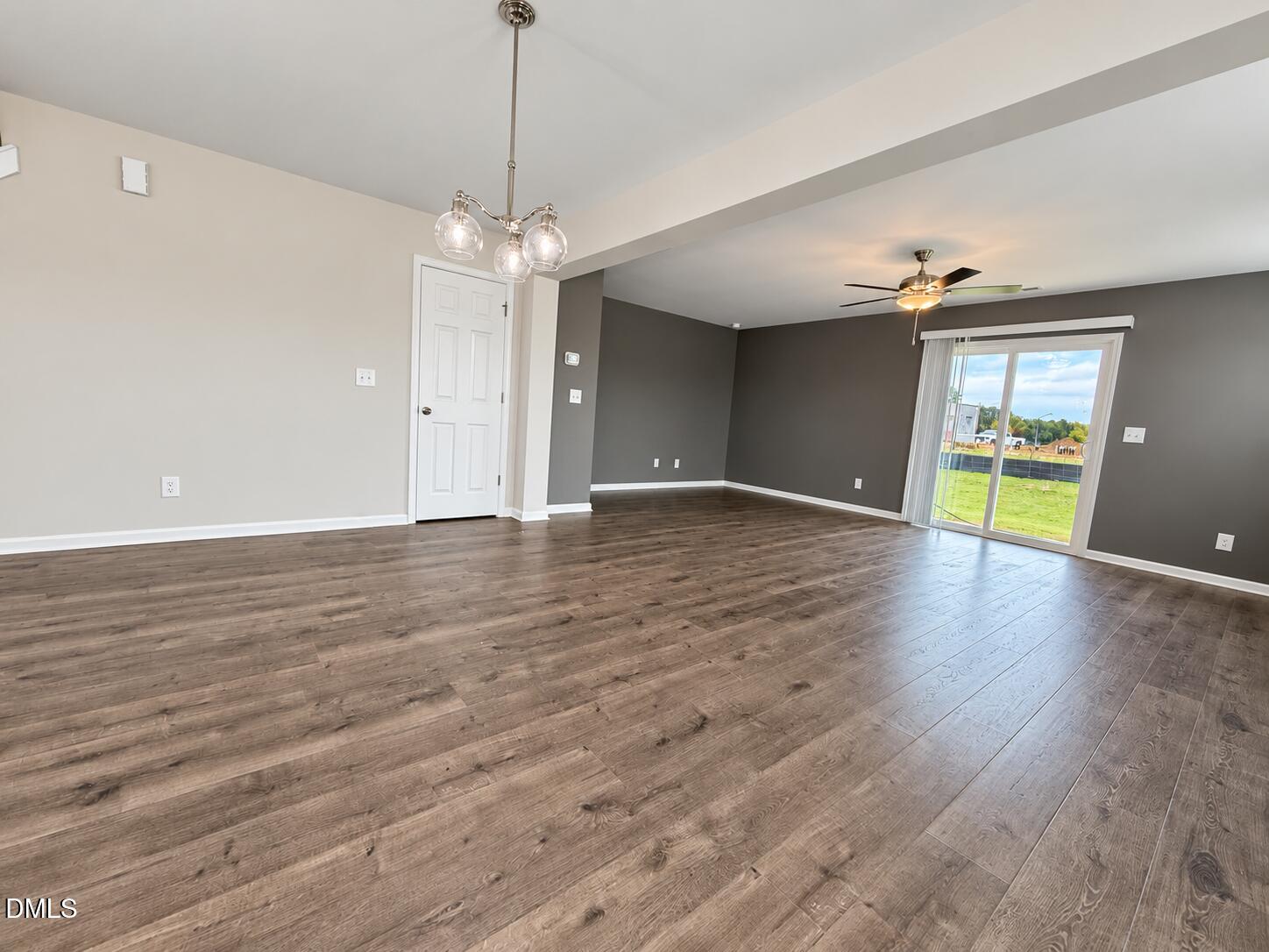 Empty living area with wood-look floors, gray walls, and a sliding glass door to the yard.