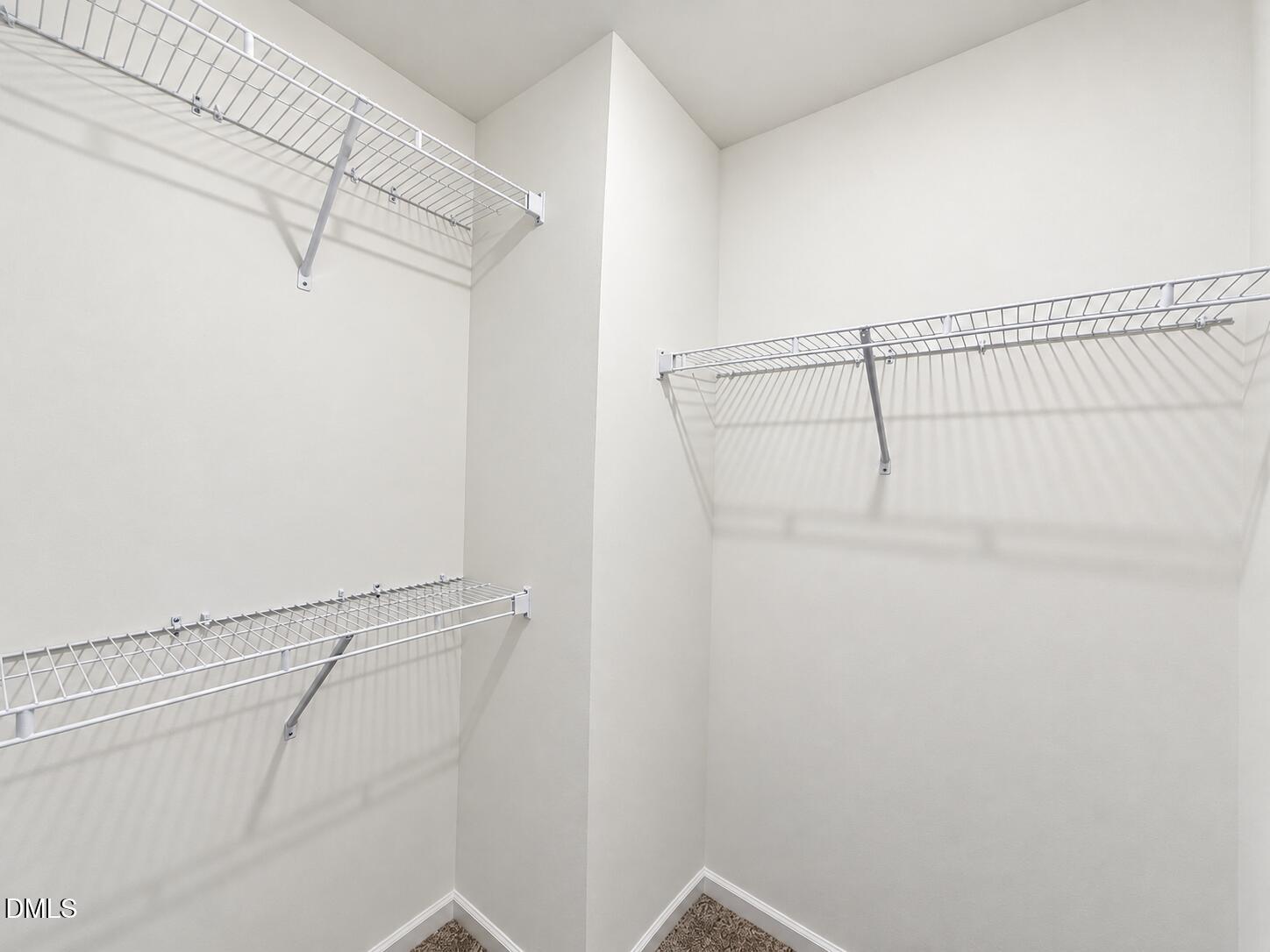 Walk-in closet with three white wire shelves and a carpeted floor.