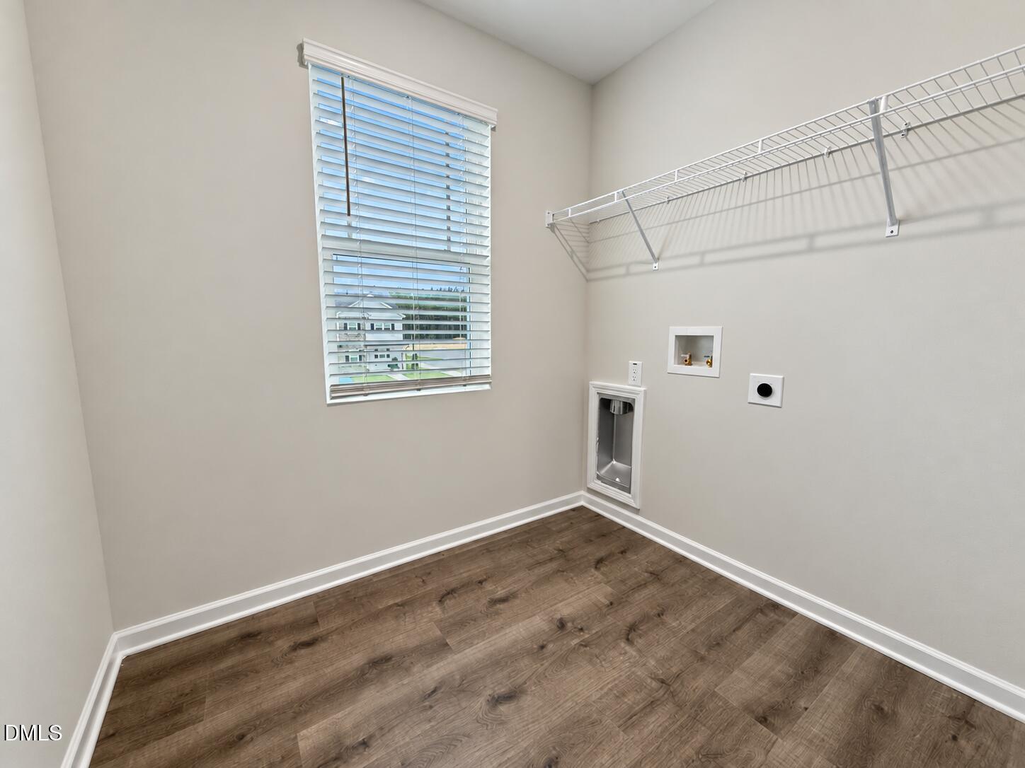 Laundry room with wood-look floors, wire shelving, and washer and dryer hookups.