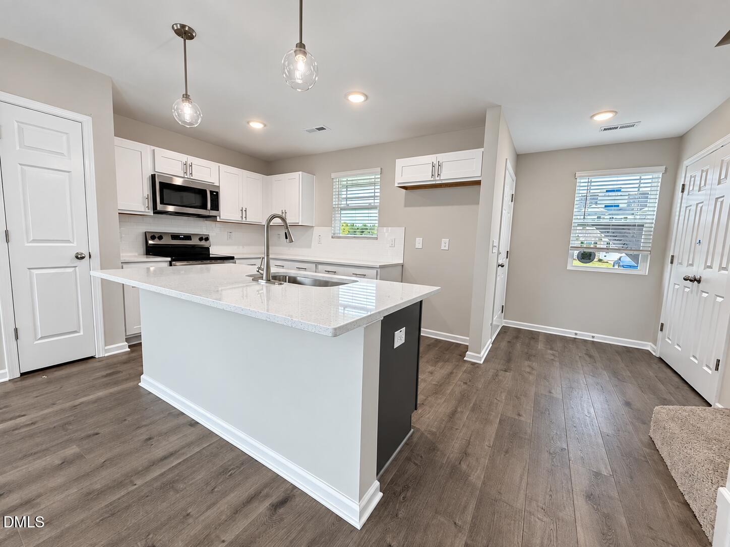 Bright kitchen with white cabinets, stainless steel appliances, and a large island with a double-basin sink.