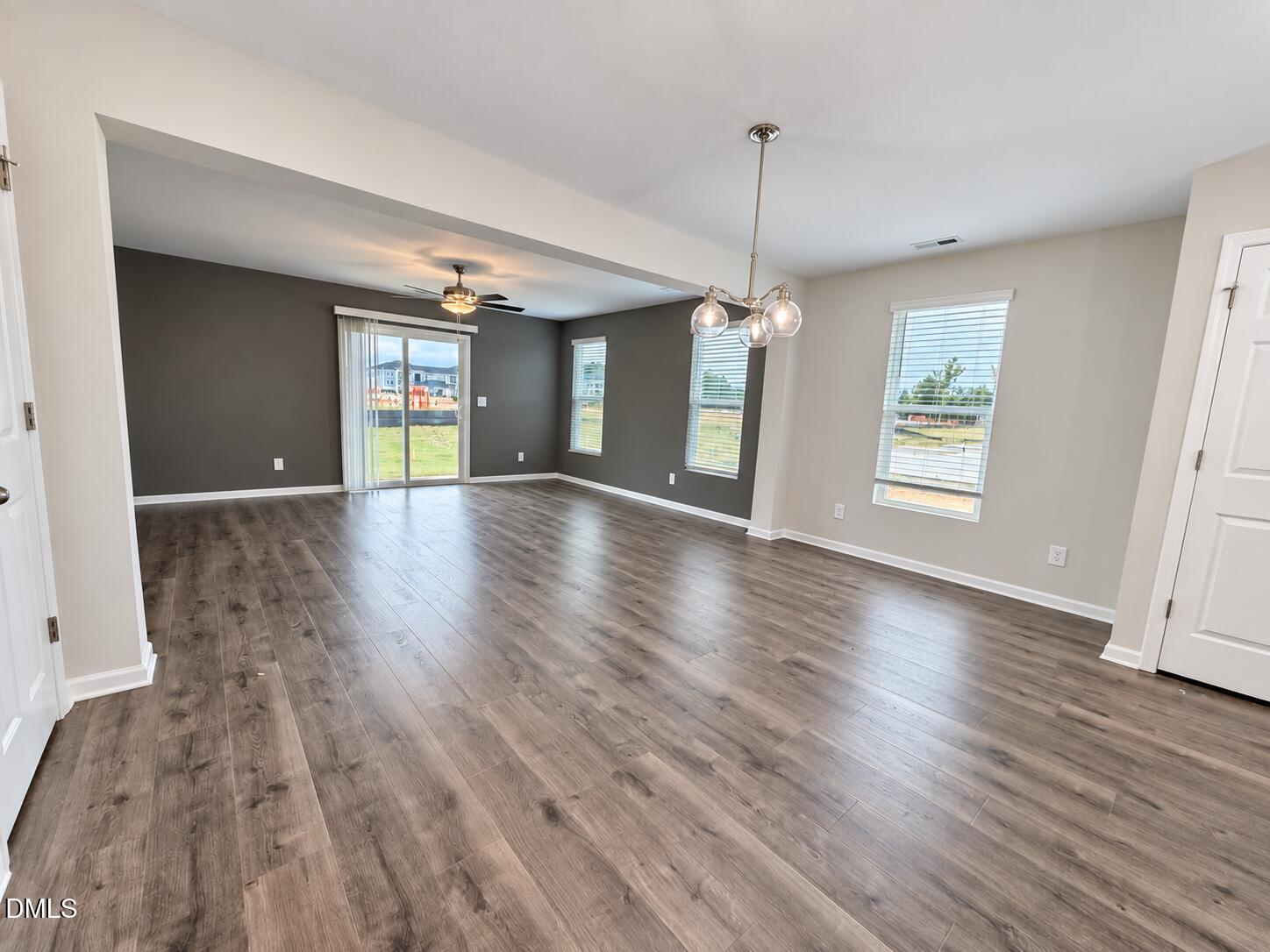 Open-plan living and dining area with wood-look floors, dark accent wall, and sliding glass door.