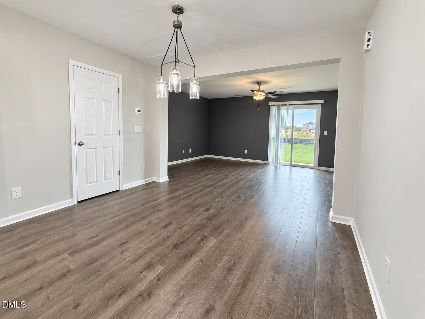 Vacant open-plan living and dining area with wood-look floors and sliding glass doors.