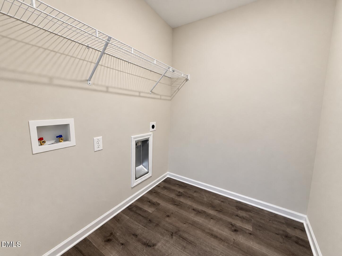 Empty laundry room with wire shelving, washer hookups, and dark wood-look flooring.