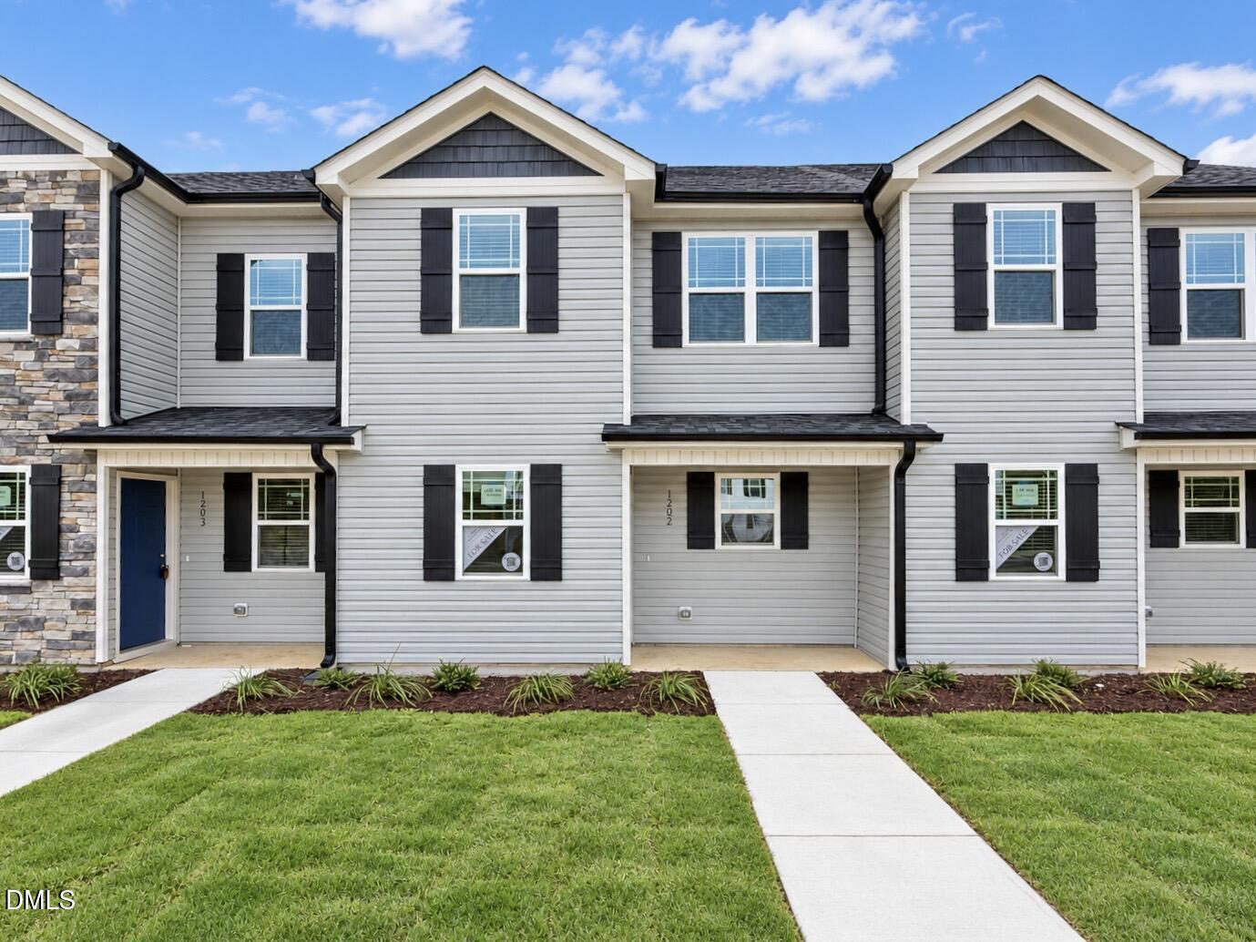 Front exterior of 1202 Brookrun Drive in Oxford, NC, with light gray siding, black shutters, a covered porch, and a landscaped walkway.