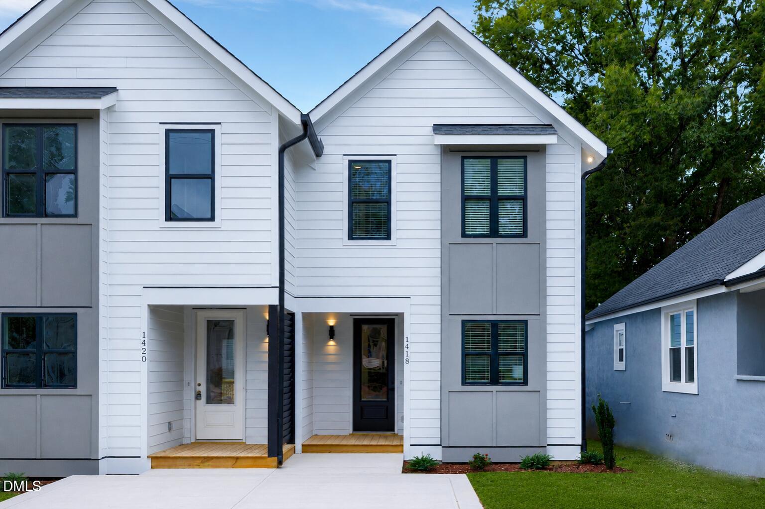 Front exterior of 1418 Joe Louis Avenue in Raleigh, NC featuring a newly constructed home with white siding, black-framed windows, covered entry porch, and modern architectural details.