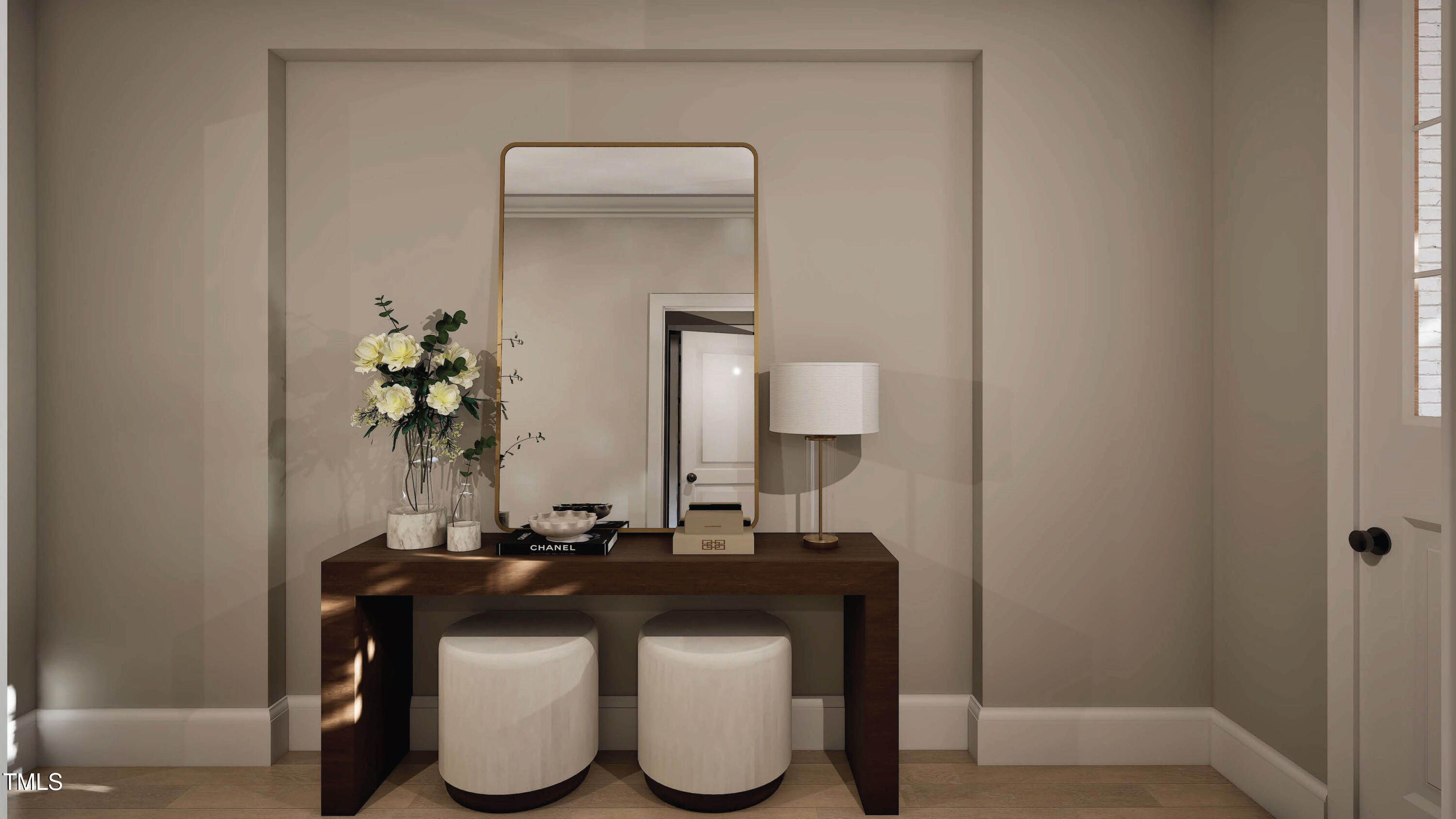 Foyer console with a gold-framed mirror, white stools, lamp, and flowers.
