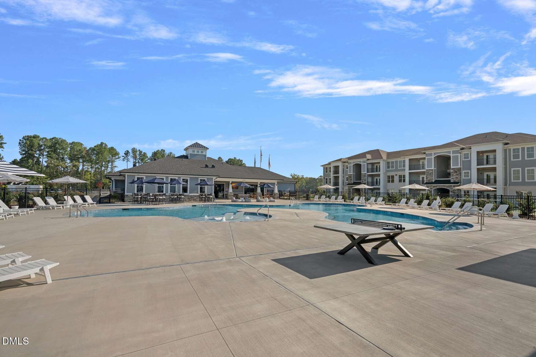 Community swimming pool and sun deck beside residential buildings and a clubhouse.