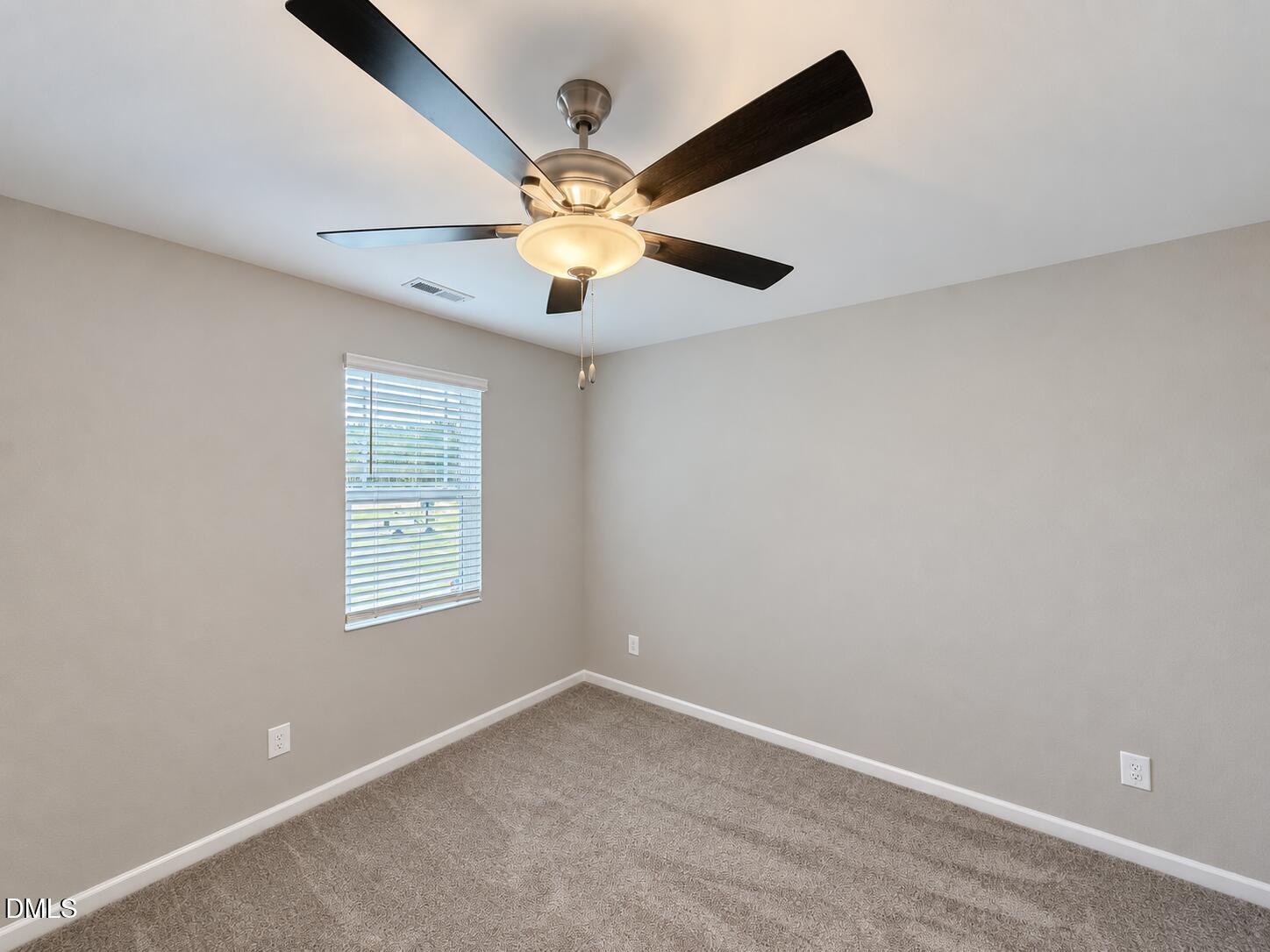 Empty bedroom with carpet, a window with white blinds, and a ceiling fan with light.
