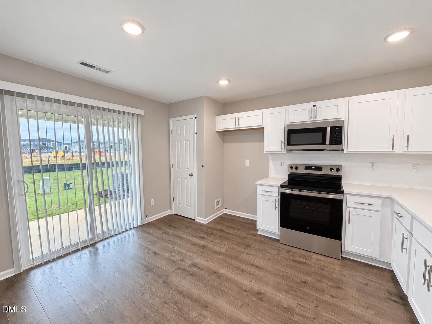 Kitchen with white cabinets, stainless steel appliances, and sliding glass doors opening to a patio.
