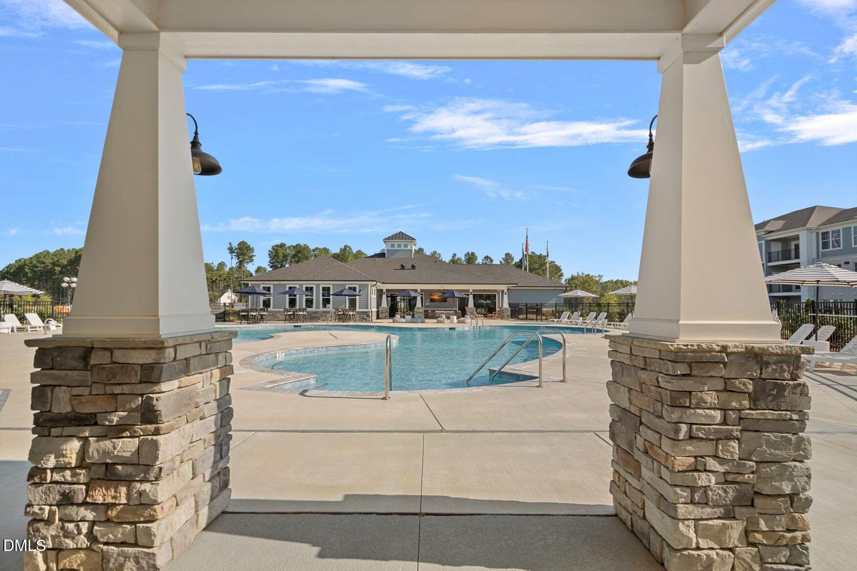 Community swimming pool and clubhouse framed by stone-based pavilion columns.