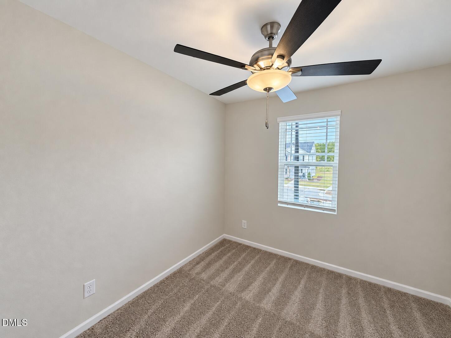 Empty bedroom with beige carpet, a ceiling fan, and a window with white blinds.