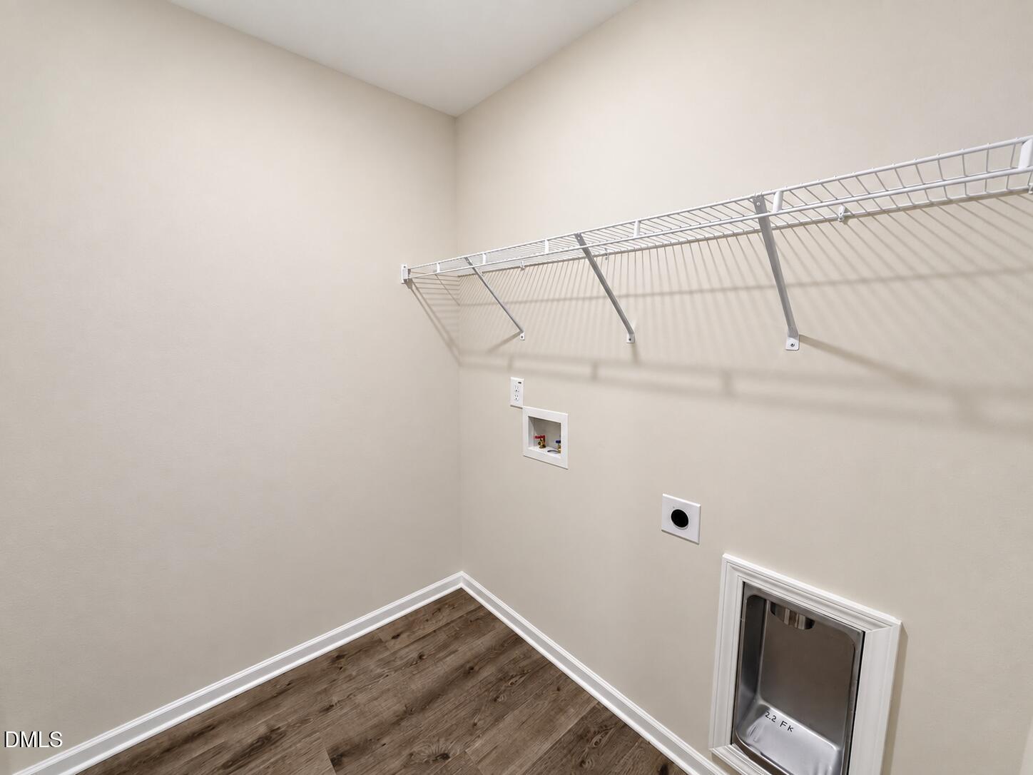 Empty laundry room with wire shelving, washer hookups, and a small pet door.